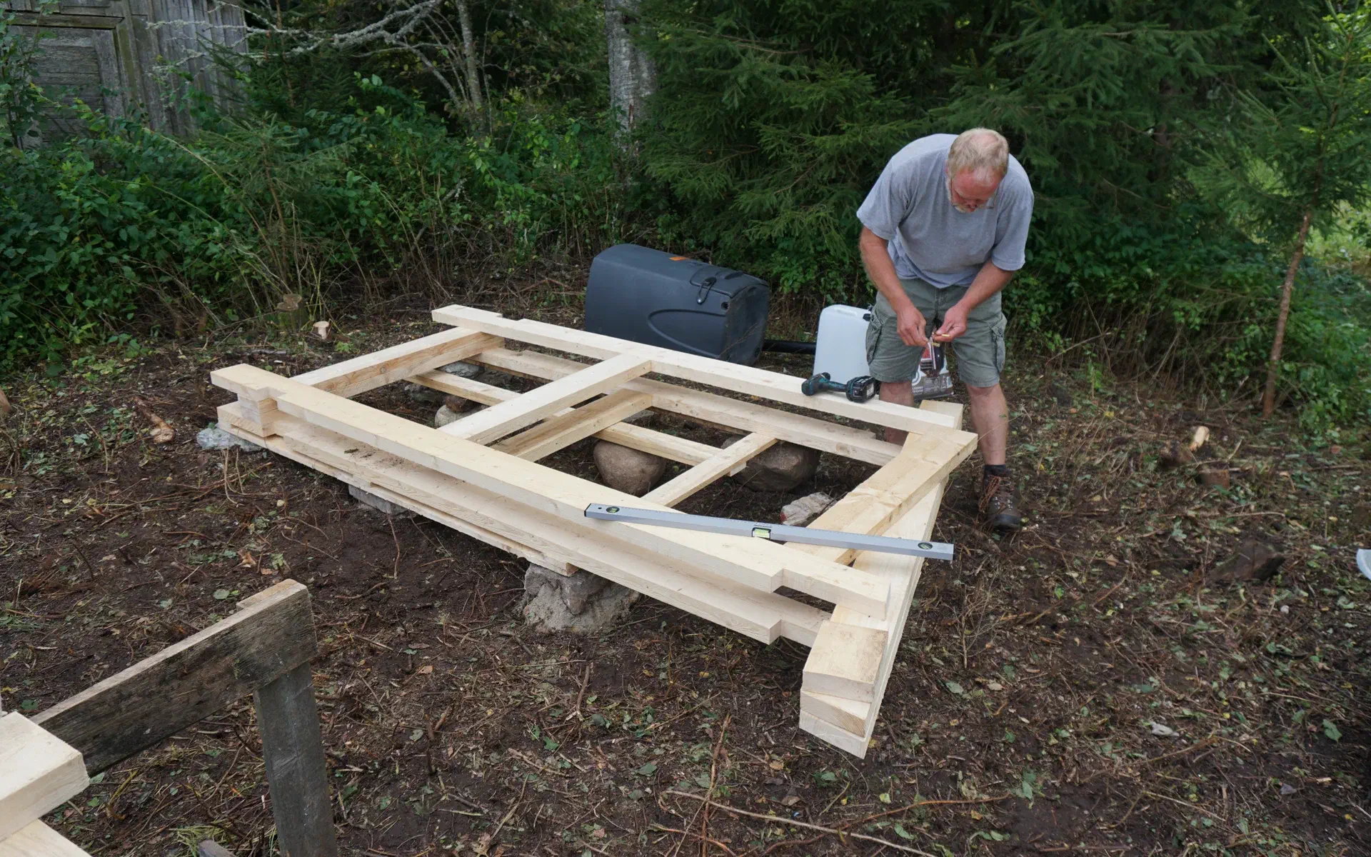 The side panels are laid out on the foundation of the outhouse. These will later form the basic framework of the structure.