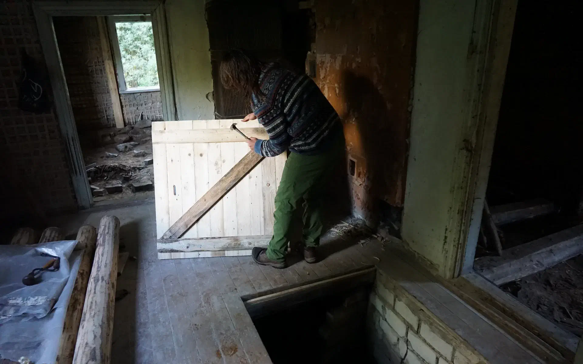 Basti installs the hatch that will cover the cellar hole in the main house.