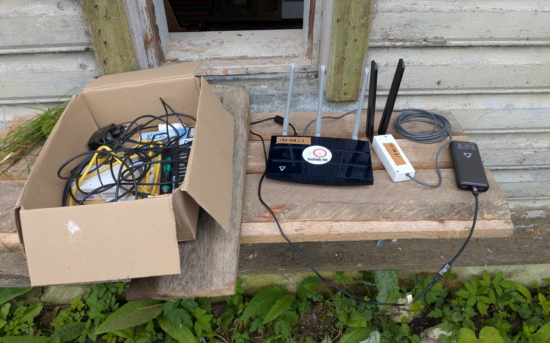 Ein WLAN-Router, eine Power Bank und eine Mobilfunkantenne auf einem Tischchen
