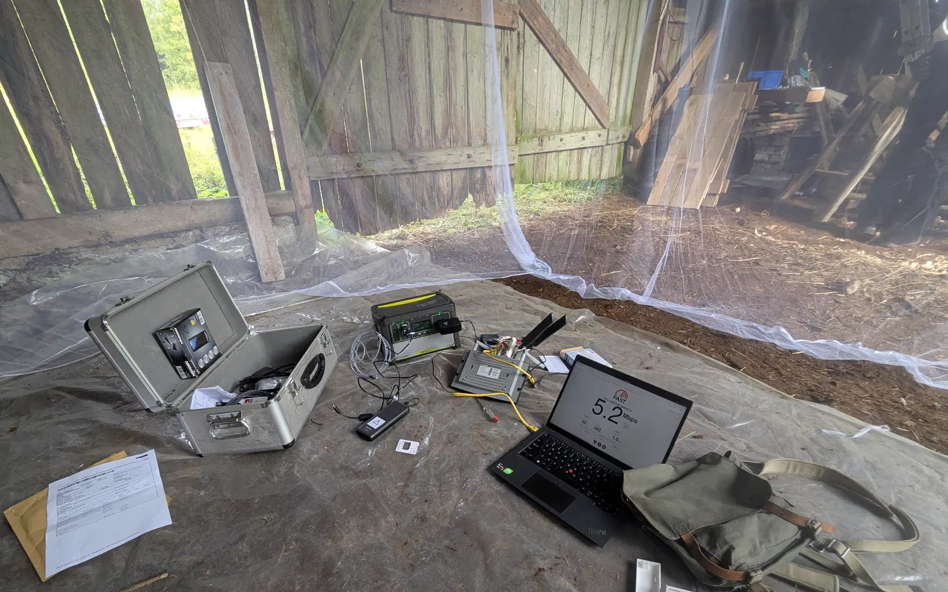 A WiFi-Router with extra 4G-Antennas is sitting under the mosquito net. Next to is, a laptop showing 5 mbps