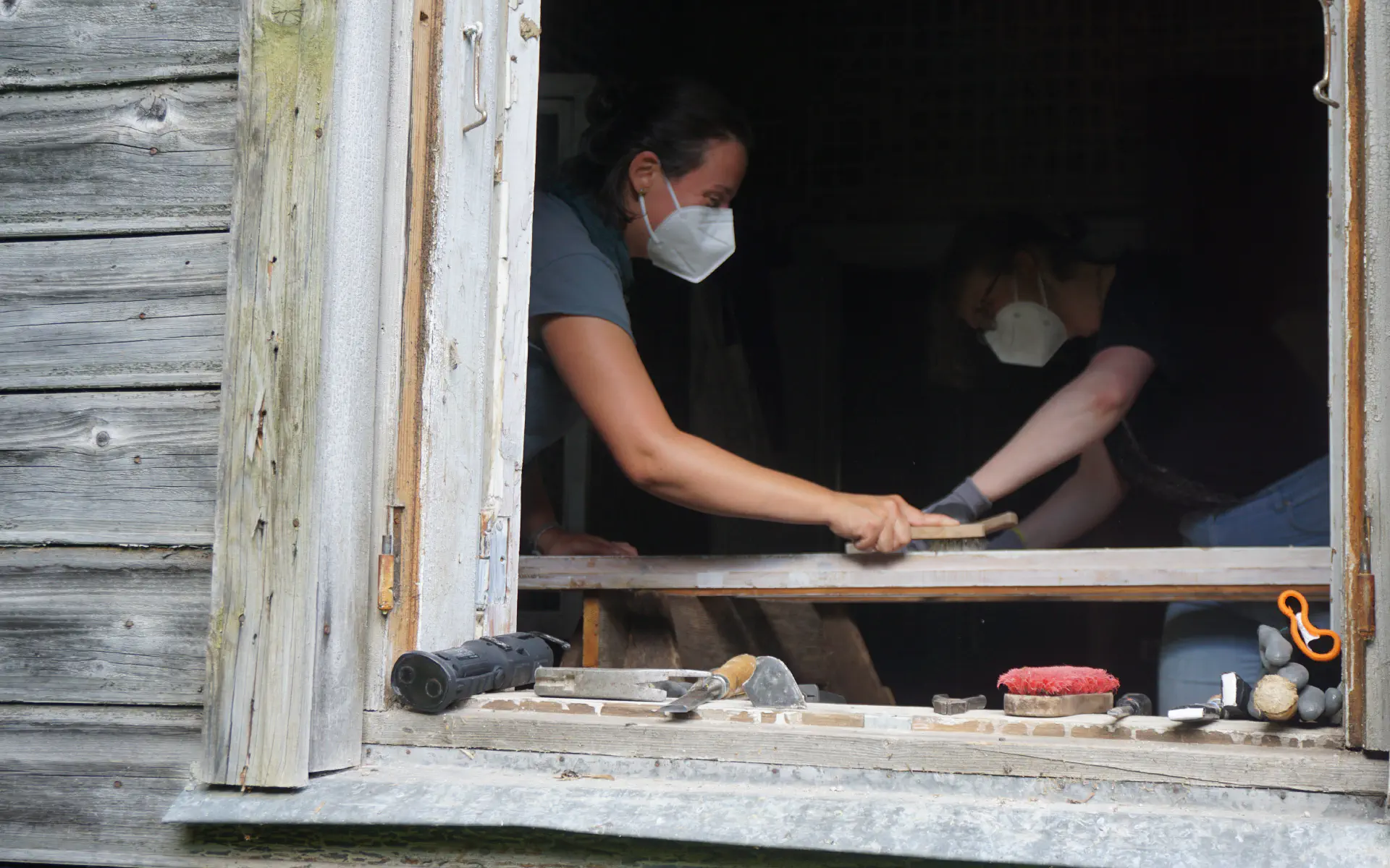Anna schrubbt Fensterrahmen mit der Drahtbürste