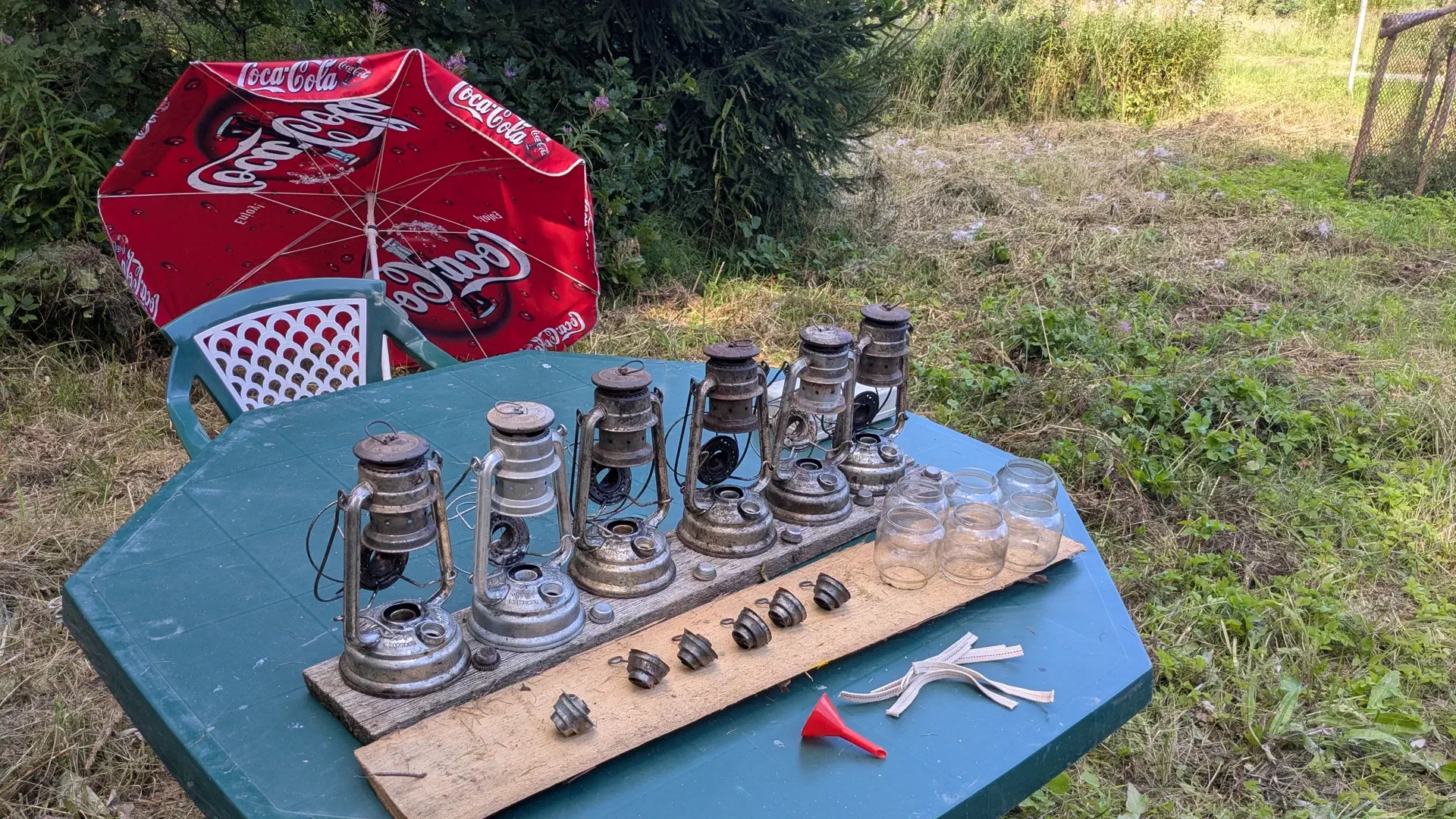 Six kerosene lamps, dismantled into individual parts and cleaned, are standing on the table.