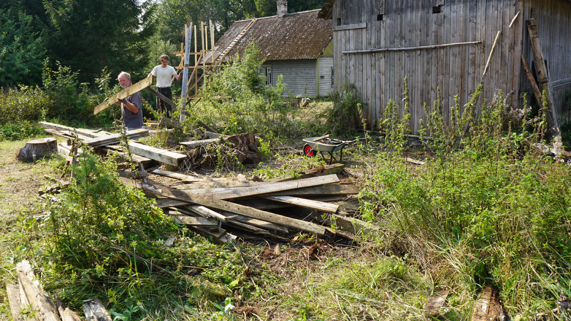 Tobias and Lukas carry some long boards away from the barn