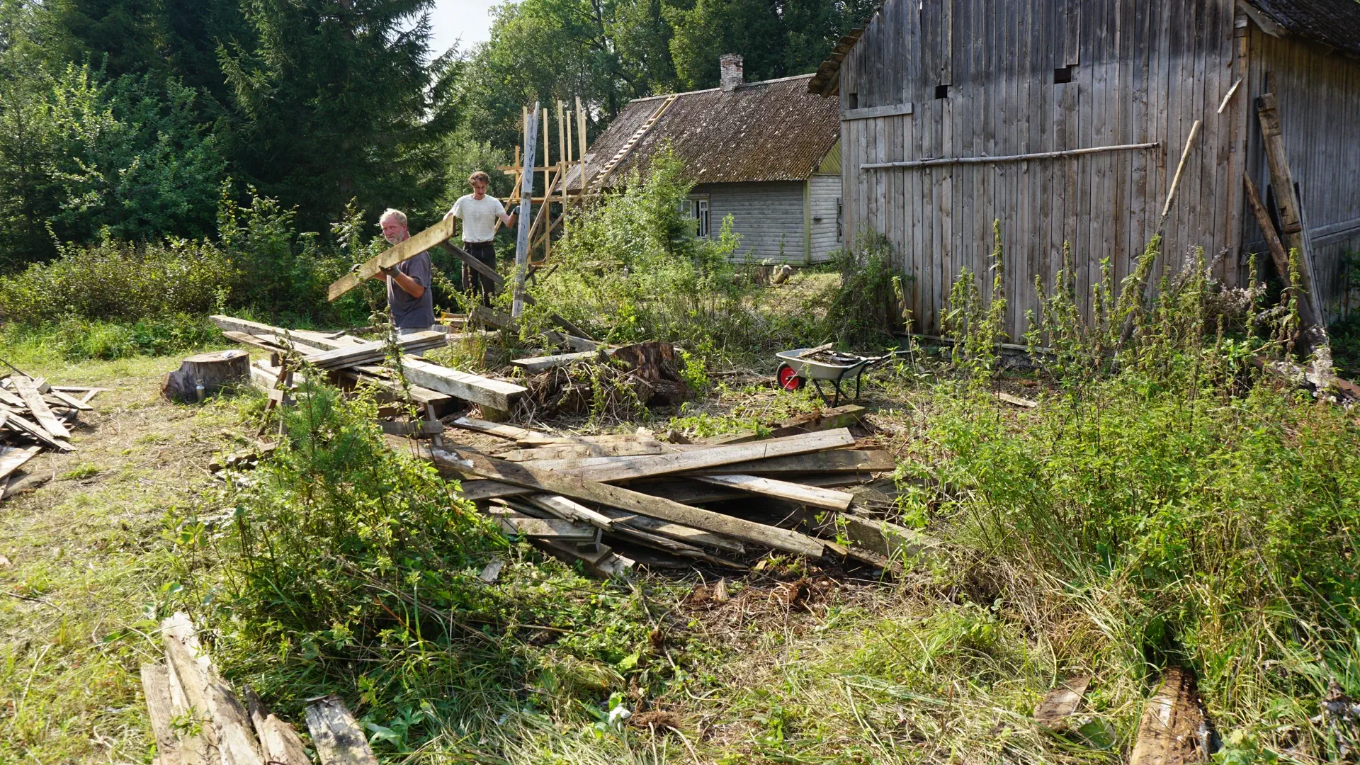 Tobias and Lukas carry some long boards away from the barn