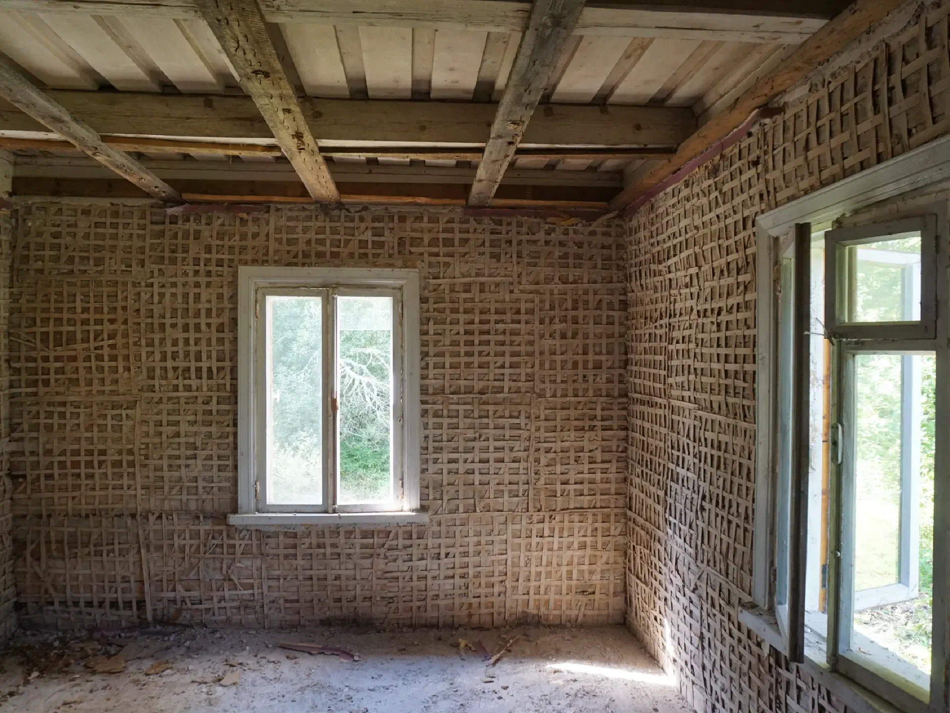 After removing the plaster, a fine grid of wooden strips appears on the log construction. Ceiling beams can be seen again on the ceiling