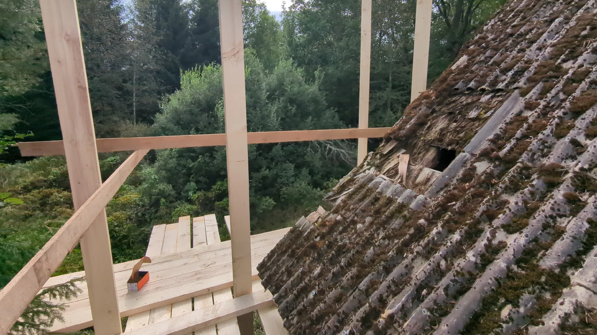 Scaffolding in the foreground. Eternit-covered roof with hole.