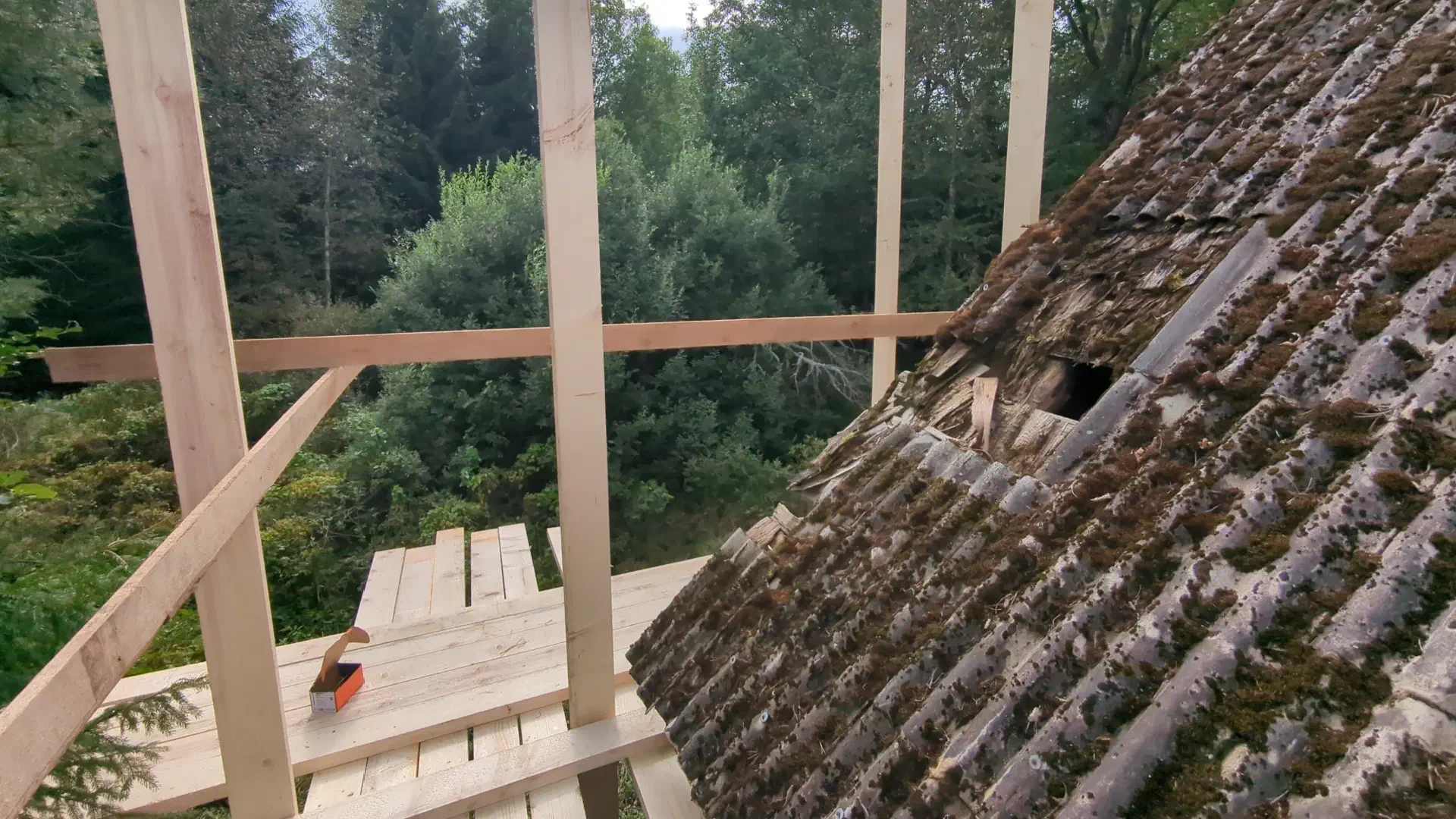 Scaffolding in the foreground. Eternit-covered roof with hole.