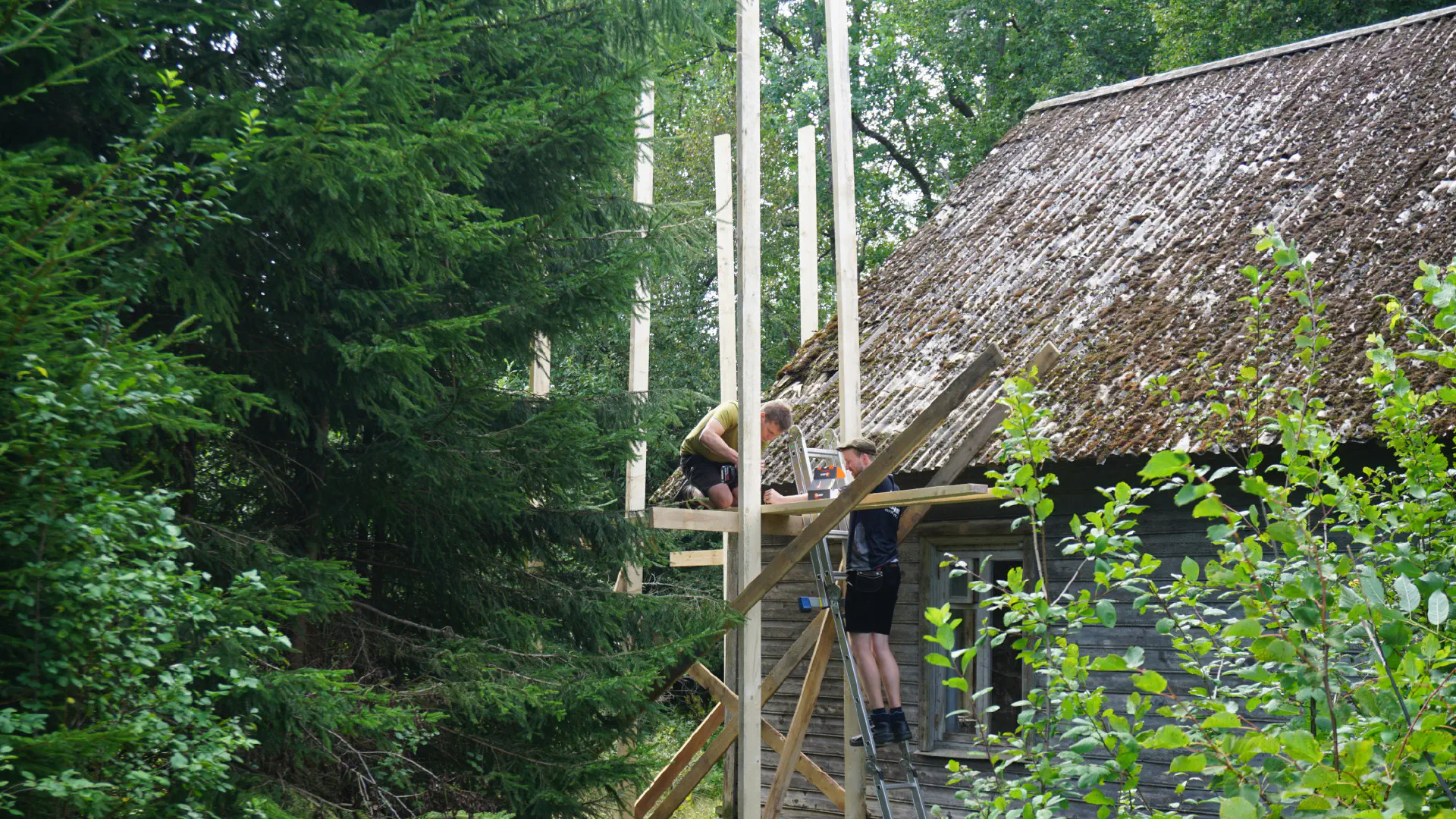 Hagen and Klaas stand on a half-finished scaffolding made of wood and screws