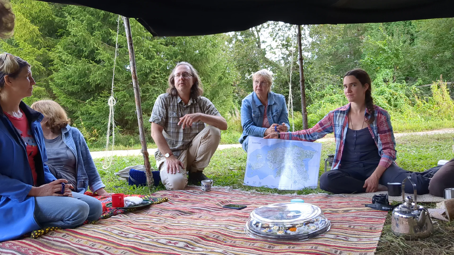 Hanno sits next to a large map of Estonia with us in the tent. Sprat bread platter in the foreground.