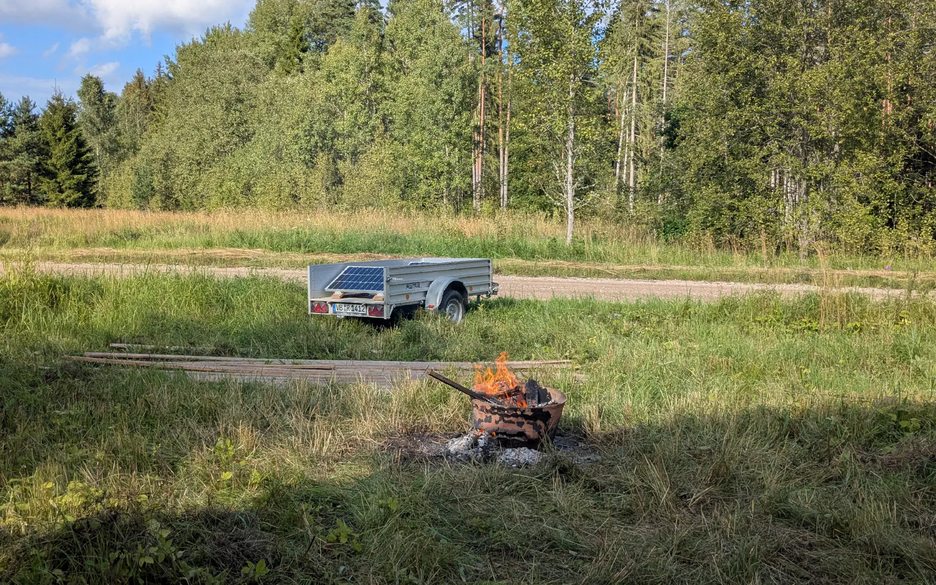 A campfire with the solar trailer in the background