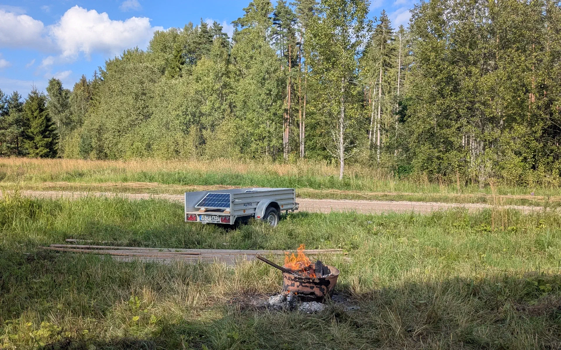 A campfire with the solar trailer in the background