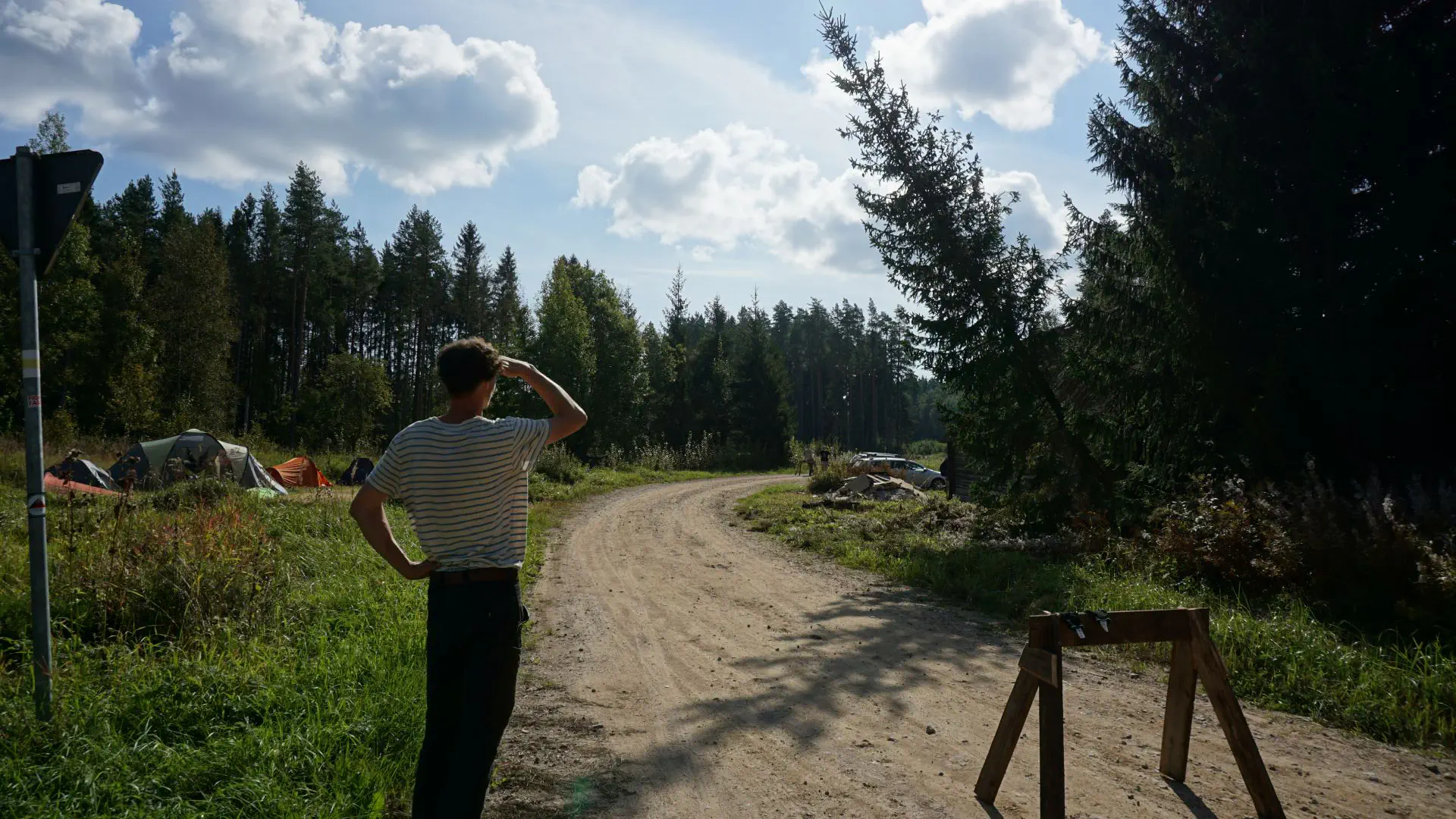 Lukas steht neben einer Straßenbarriere und schaut den Fällarbeiten zu