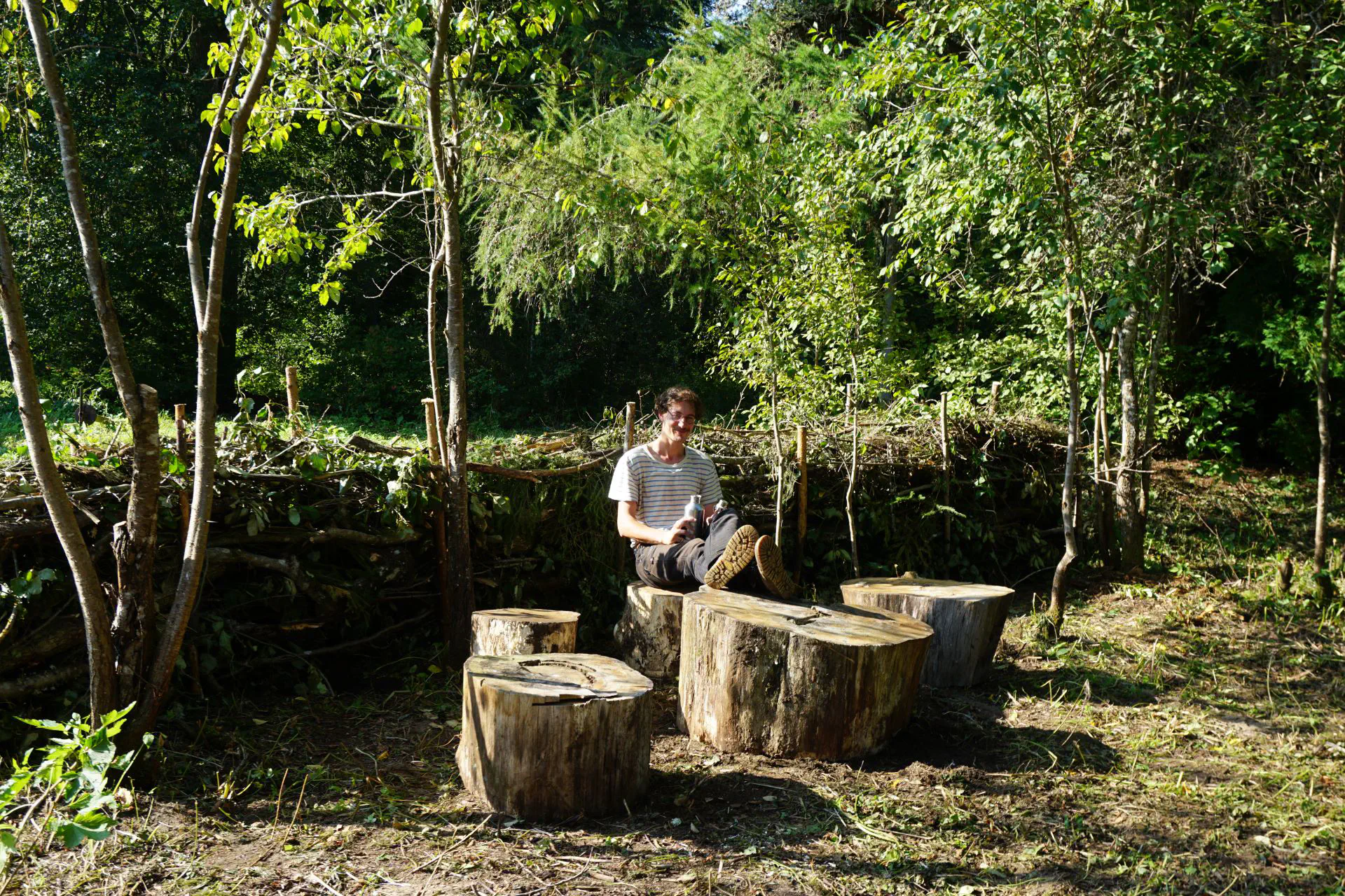 Lukas sits on our new tree stump seating area and puts his feet up