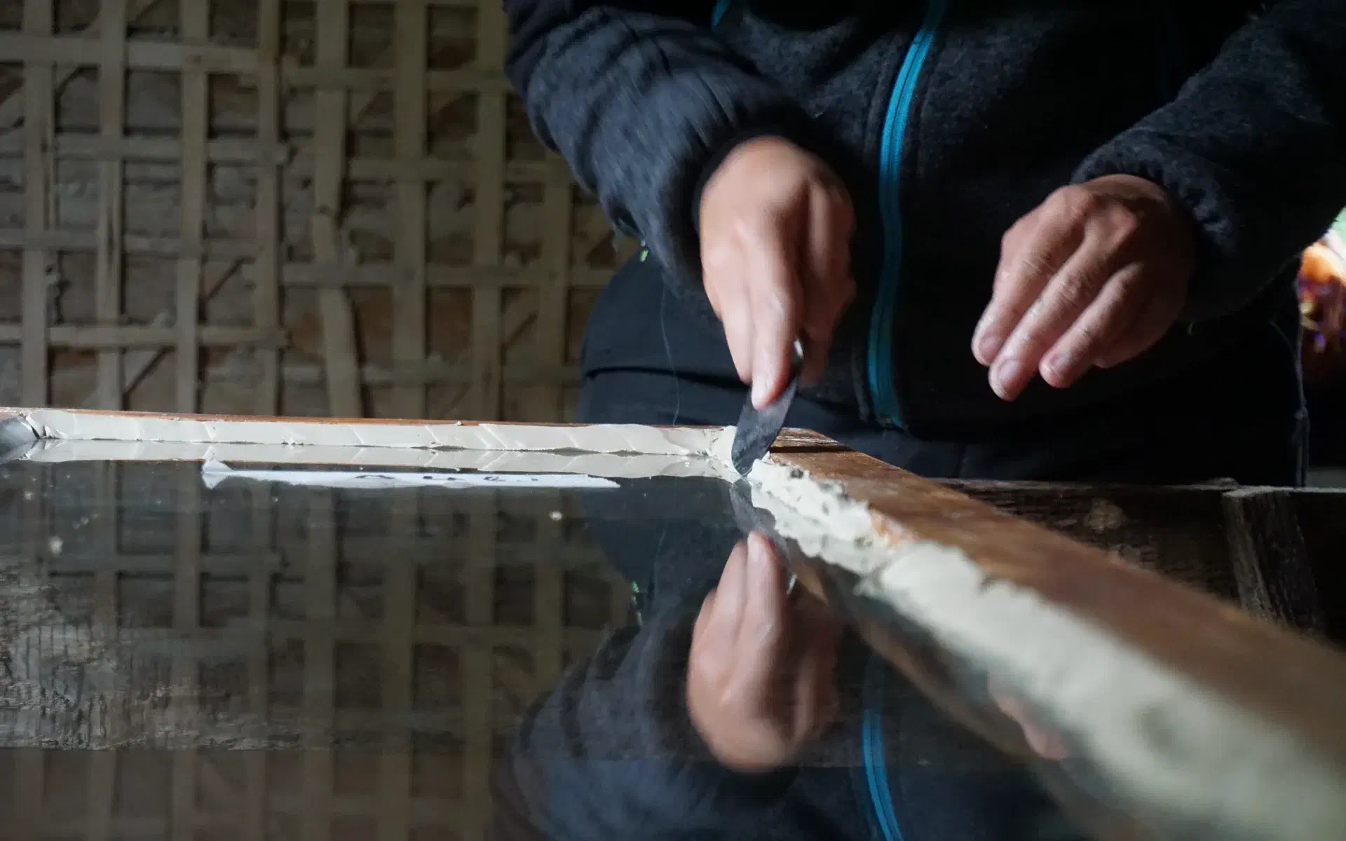 Anna fills the joints of a window with putty.