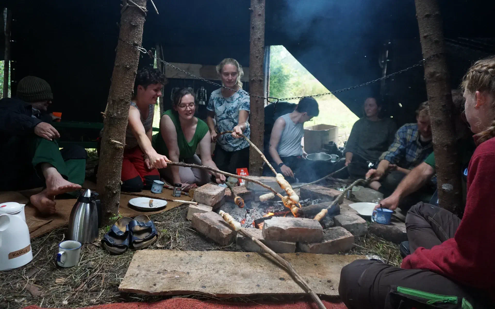 The group bakes cinnamon rolls on sticks over the campfire.