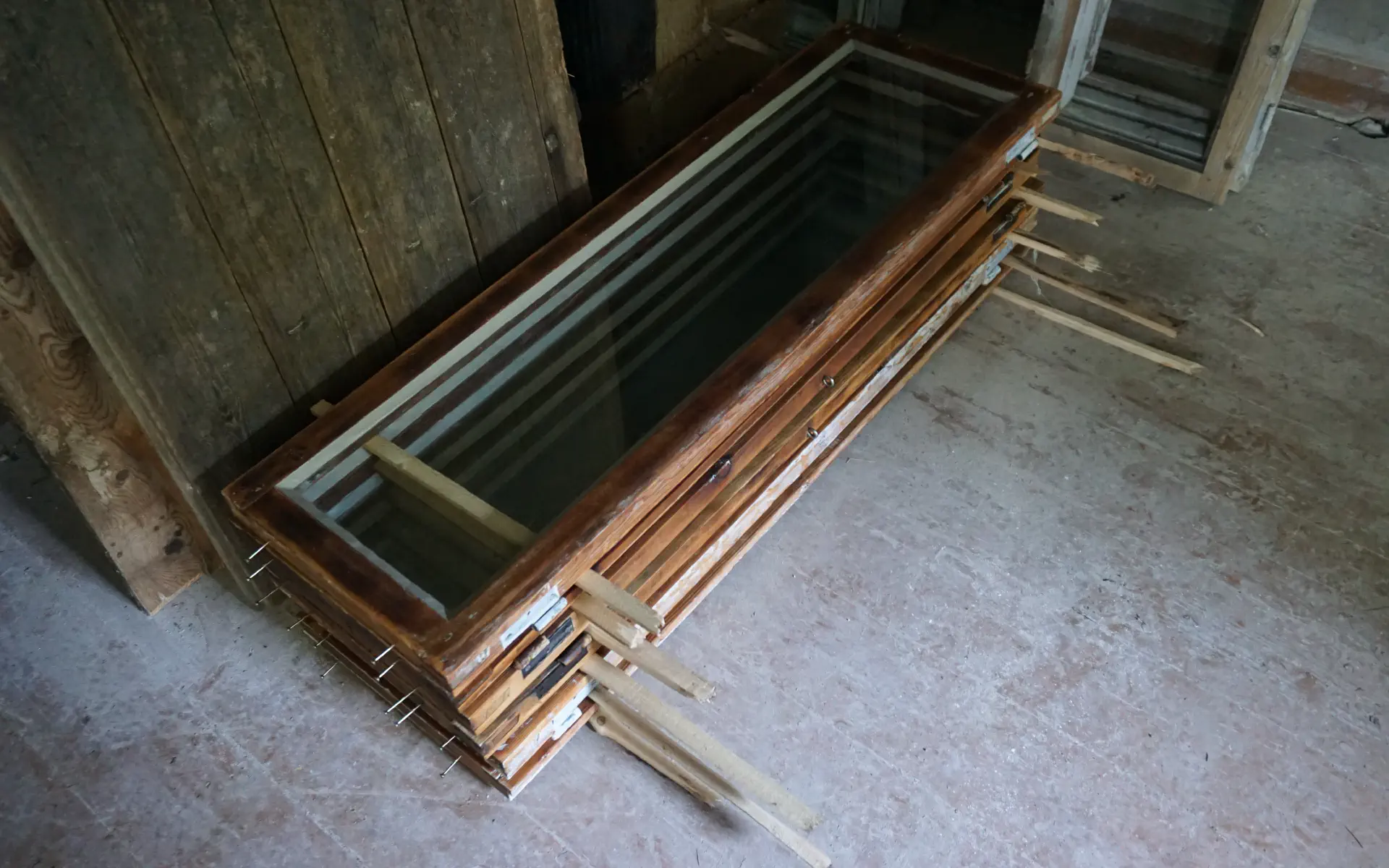 Die fertigen Fenster liegen zum trocknen aufeinandergestapelt. Leisten zwischen ihnen sorgen für Belüftung.