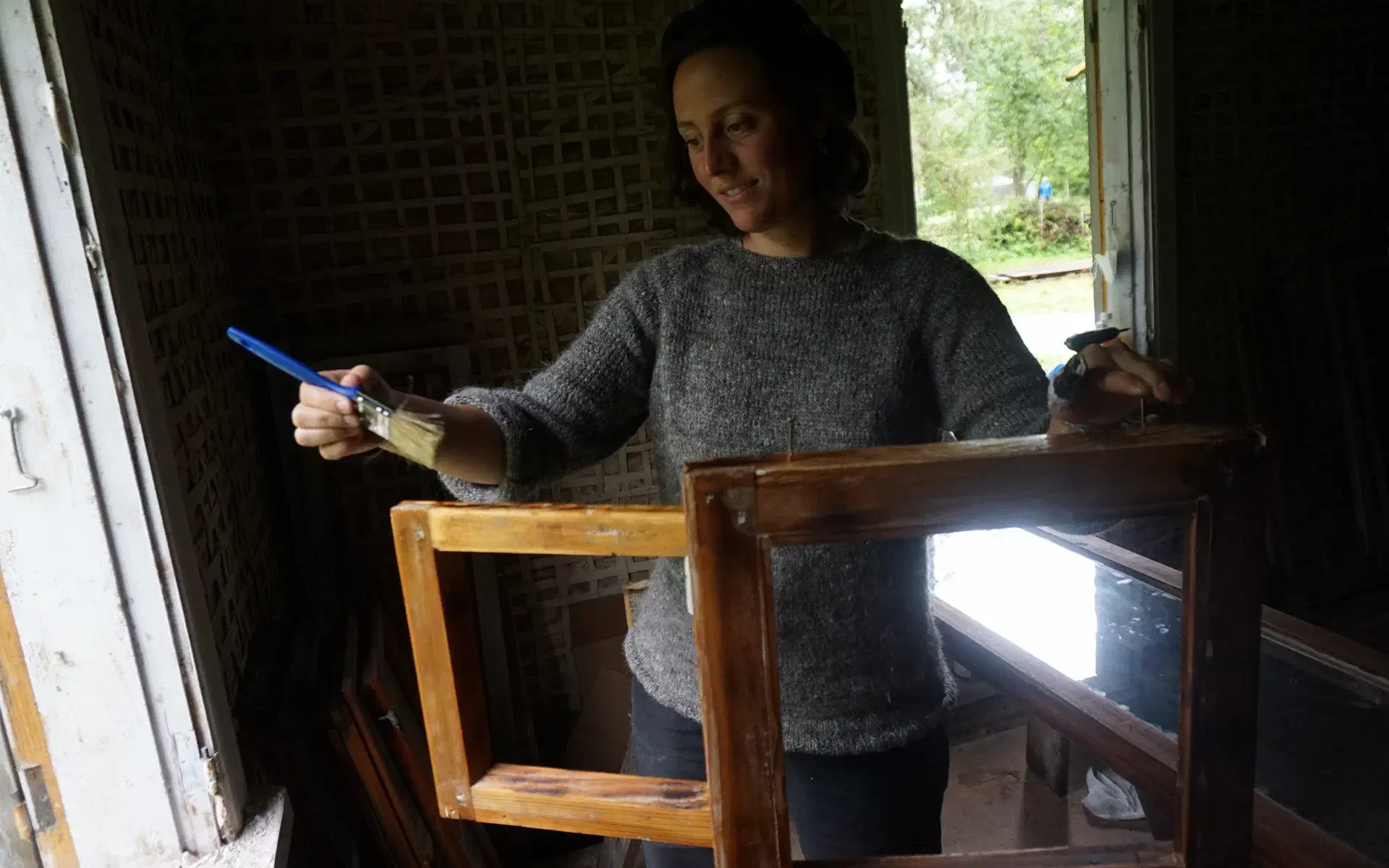 Anna applies linseed oil to a sanded window frame with a brush.