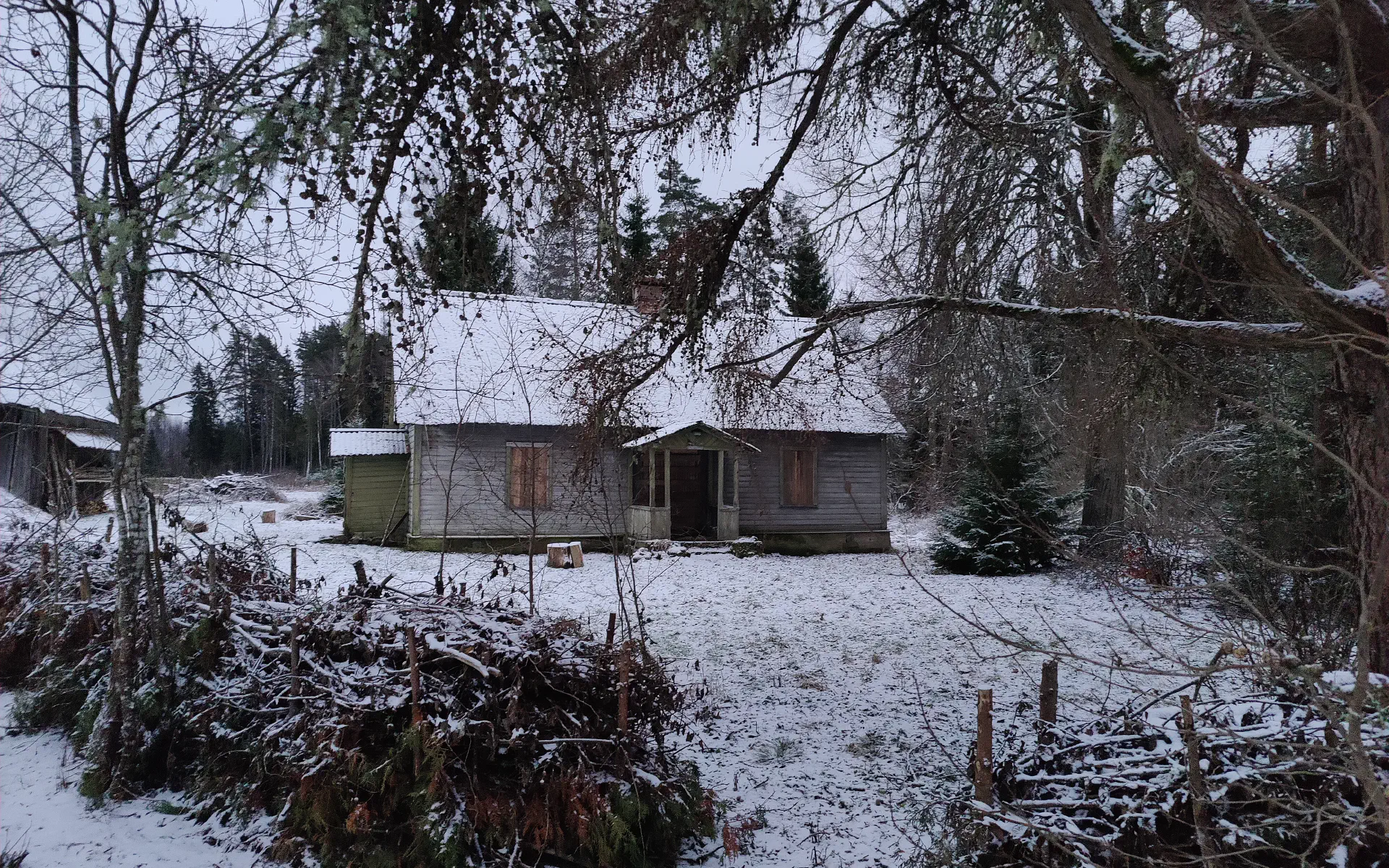 Das Haupthaus steht etwas versteckt hinter Bäumen. Alles ist leicht von Schnee bedeckt.