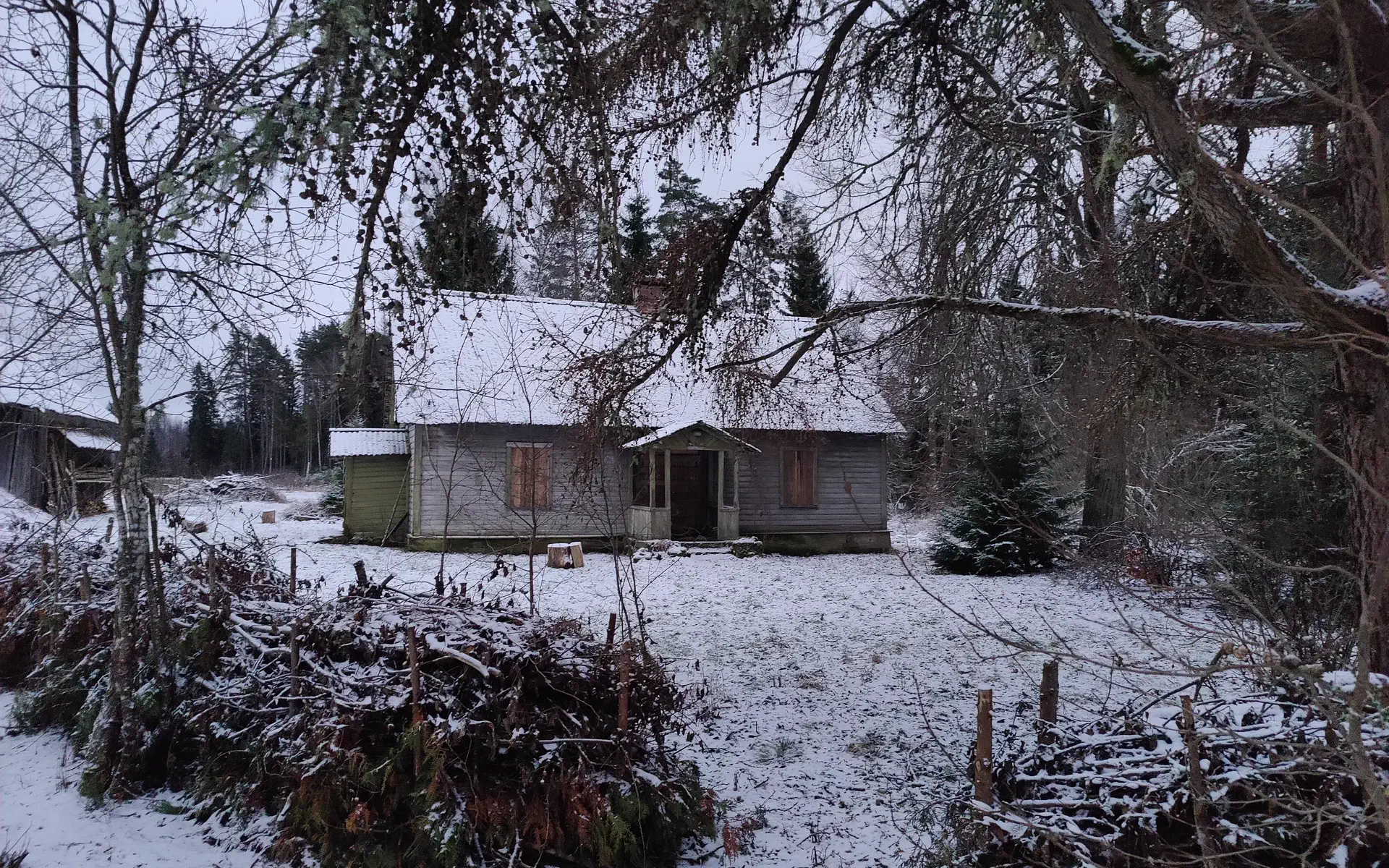 The main house is somewhat hidden behind trees. Everything is lightly covered with snow.