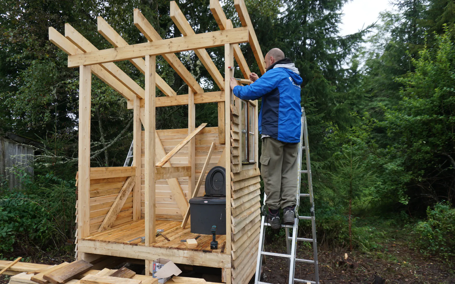 Das Kompostklo ist eingebaut und Jonas bringt die Verschalung am Grundgerüst an.