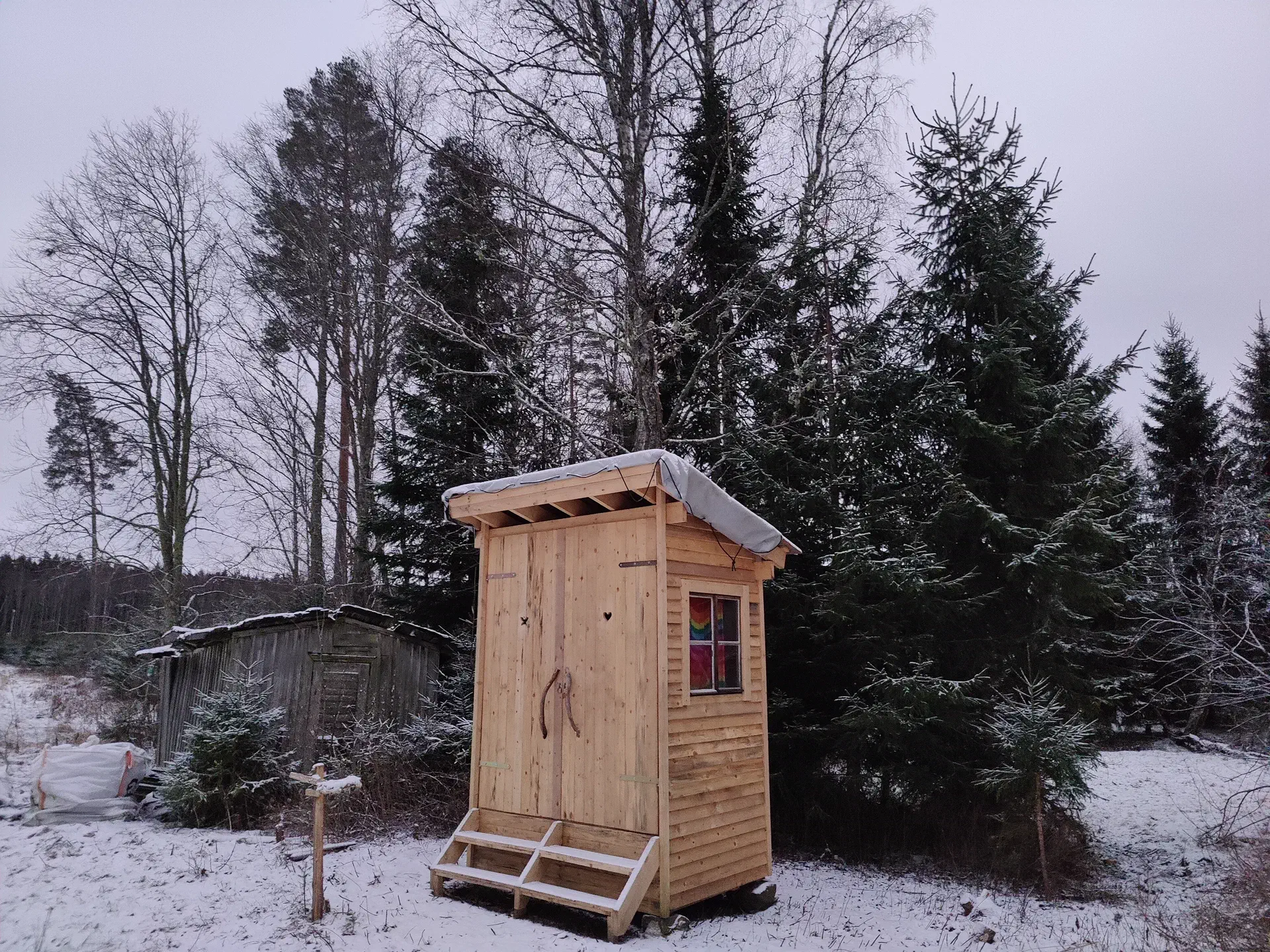 The outhouse is finished and covered with light snow.