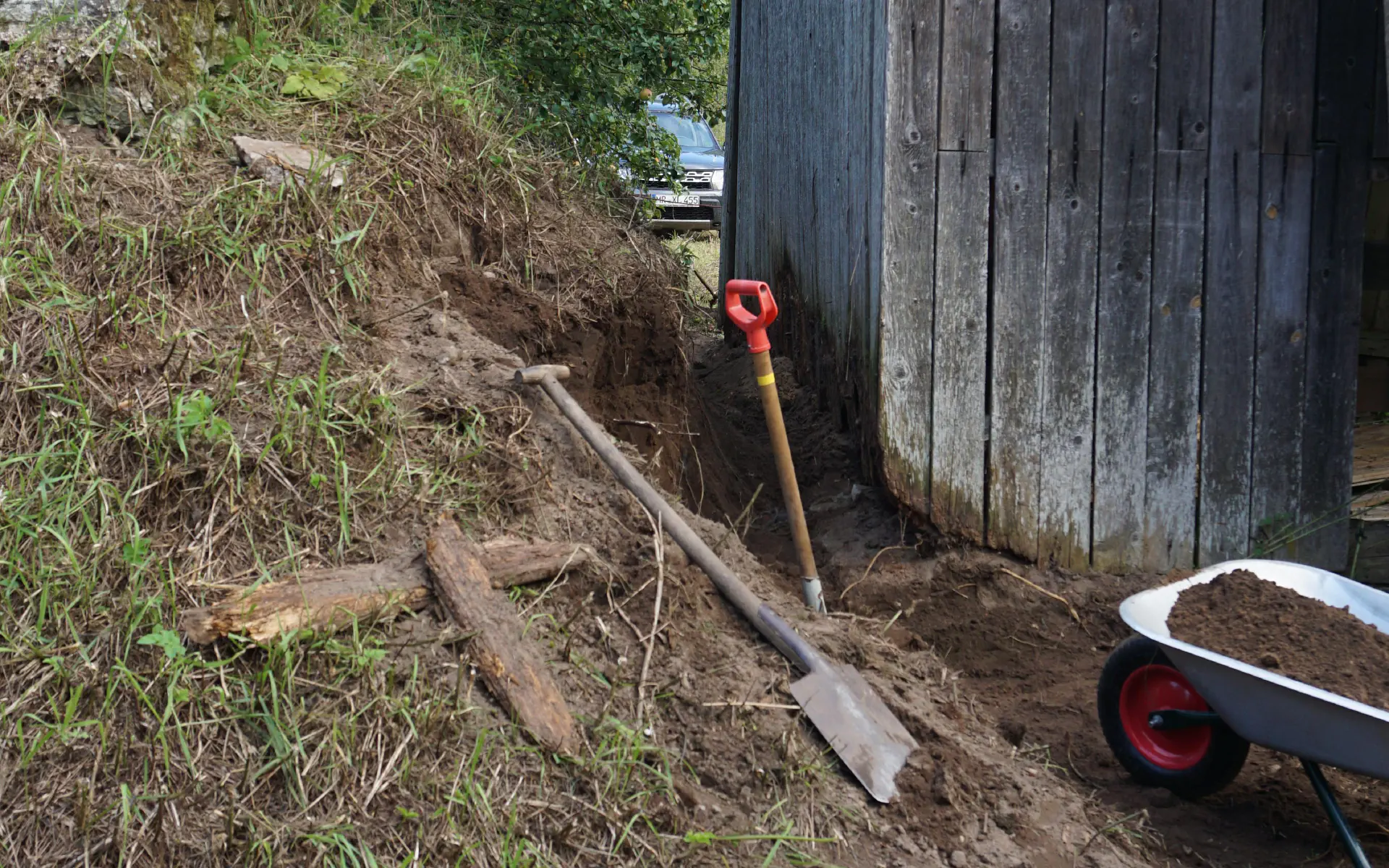 Zwischen altem Erdkeller und Scheune wurde die Erde entfernt, sodass die Scheunenwand wieder freiliegt.