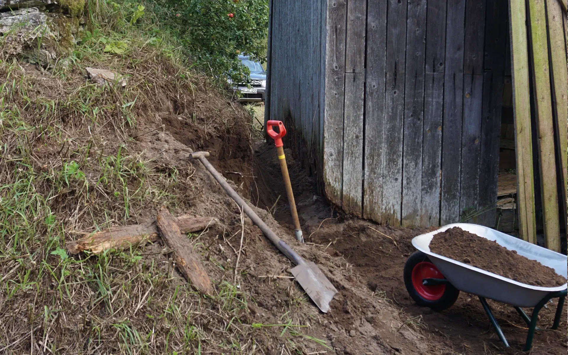 The soil was removed between the old earth cellar and the barn, exposing the barn wall again.