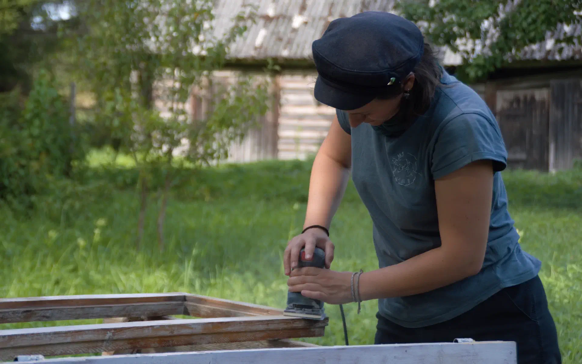 Anna is sanding a window outside on the lawn.