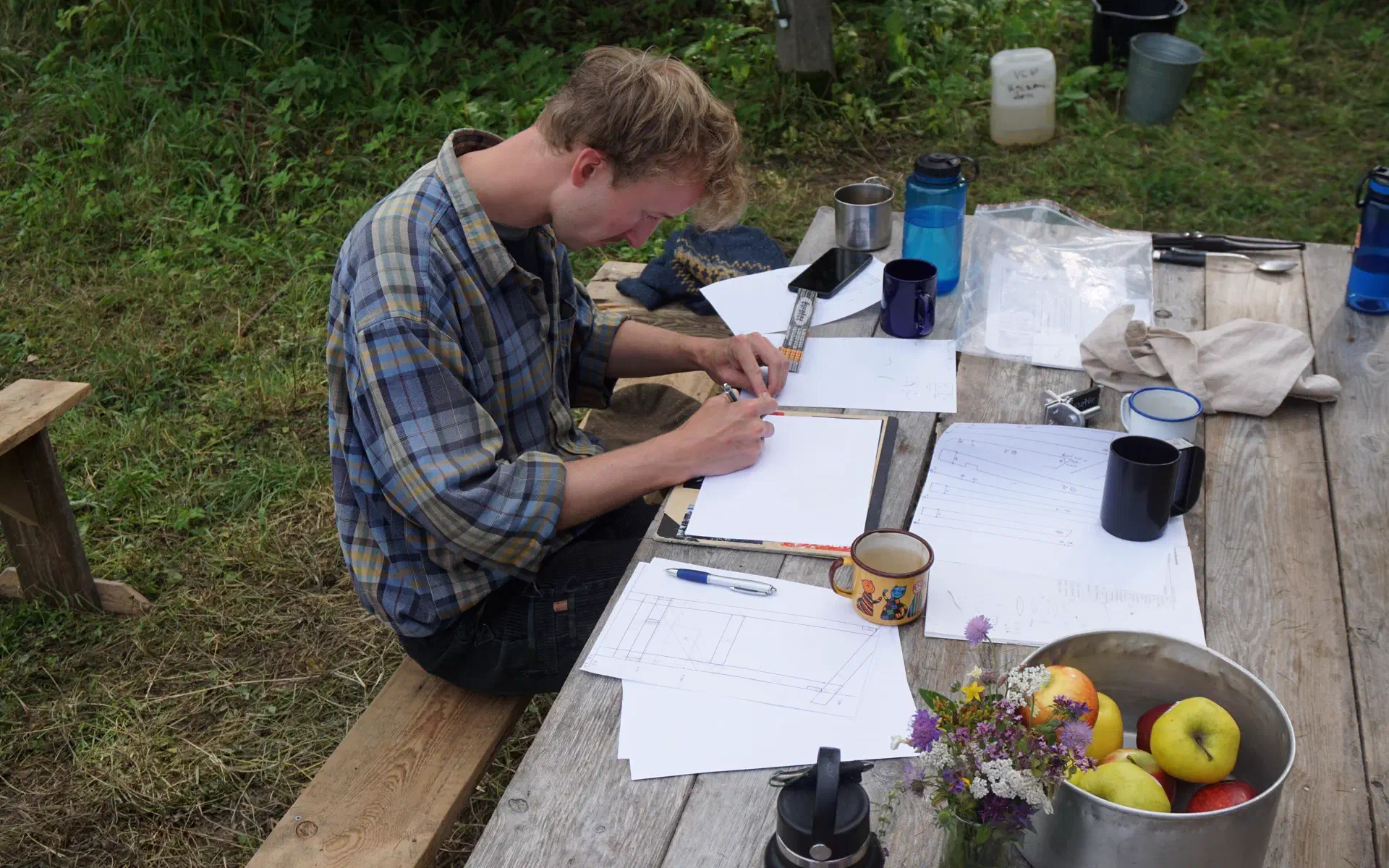 Klaas sits at a table in front of a pile of paper and draws.