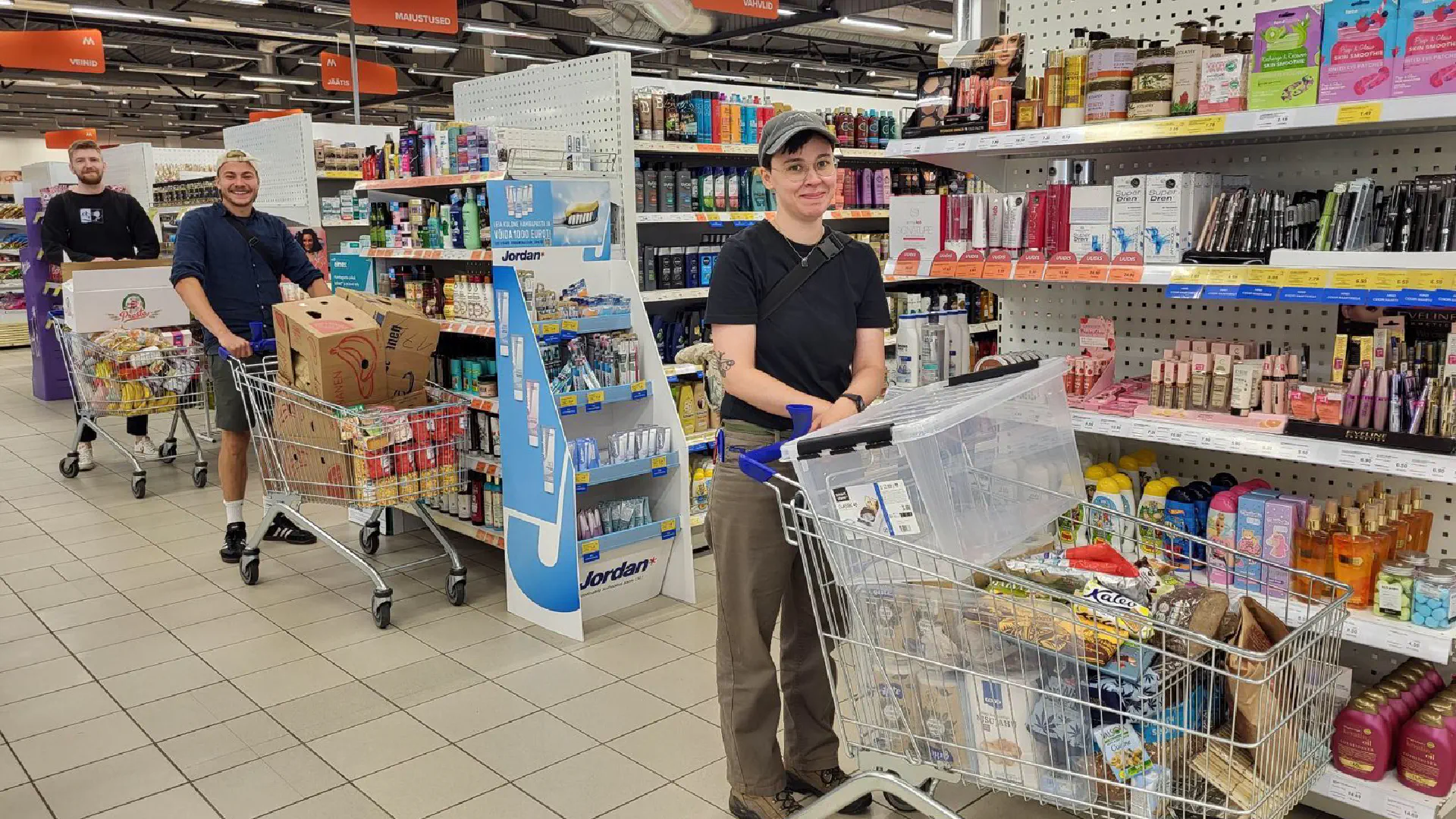 Georg, Jo und Janne fahren drei prall gefüllte Einkaufswagen durch den Supermarkt