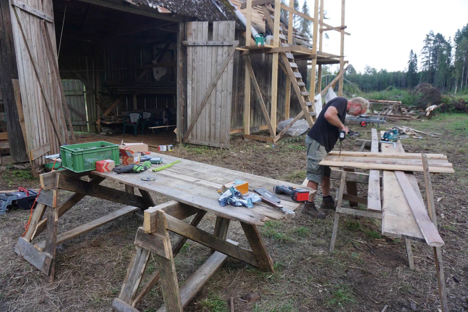 The other Tobi screws together new shutters in front of the barn