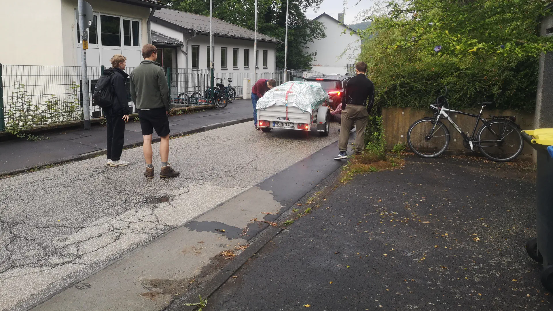 The trailer is attached and three people are standing around it. A light test is being carried out.