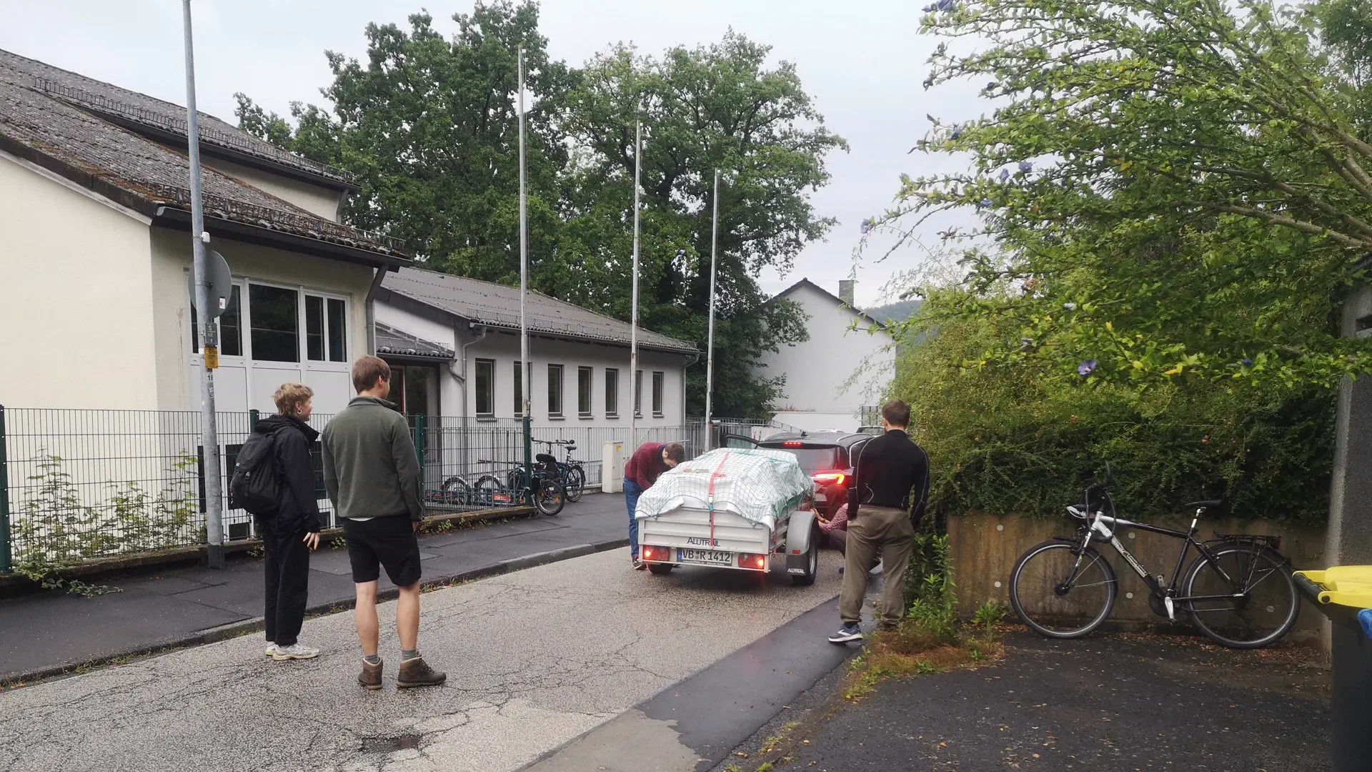 The trailer is attached and three people are standing around it. A light test is being carried out.