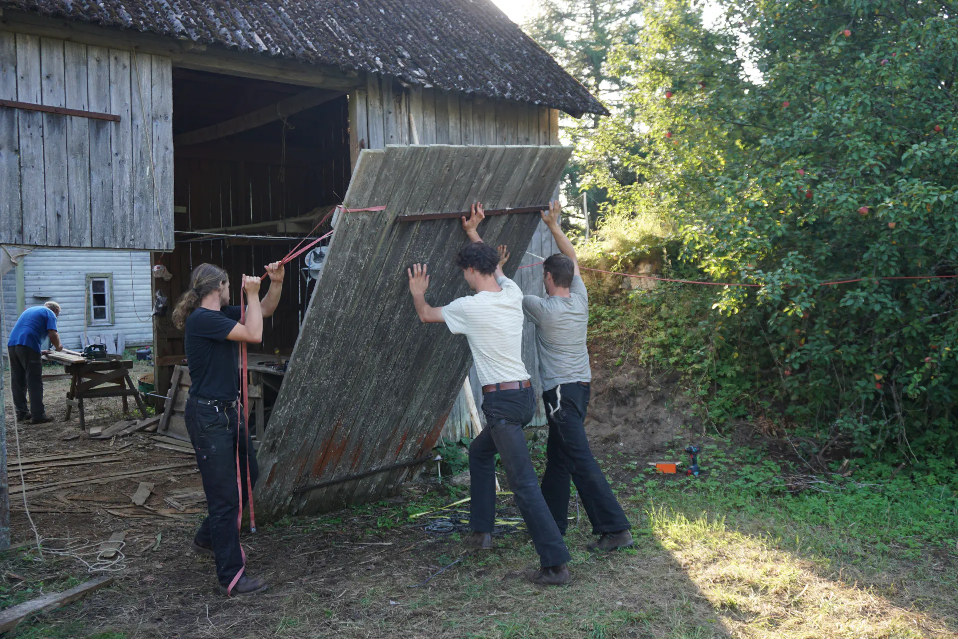 The barn door is re-hung by three people.