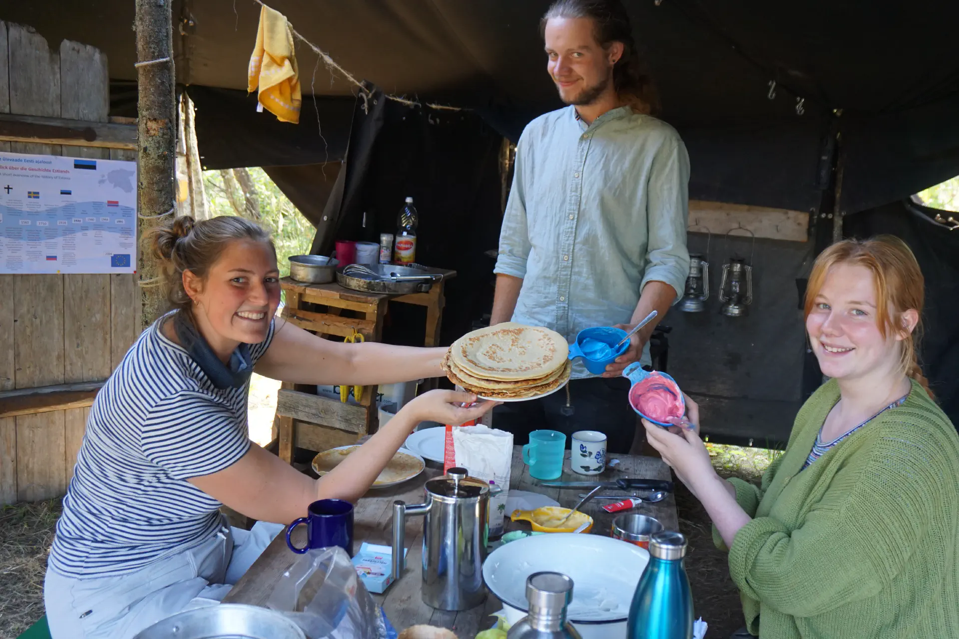 Three happy faces present a pancake-cake